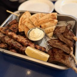 Platter with lamp chop, chicken skewers, sausage, etc. pita and cucumber dip