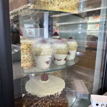 Mazzetti's Bakery - A glass display case contains a large sprinkled cake, parfaits with strawberries, and a chocolate cake with a single strawberry on top. - Bakeries Near Me - Pacifica, California