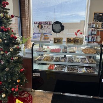 Ganache Bakery - A decorated Christmas tree with red and gold ornaments is positioned beside a bakery display case filled with assorted pastries and desserts. - Bakeries Near Me - Morton Grove, Illinois