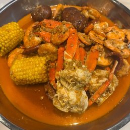 a bowl of crab legs, corn and potatoes