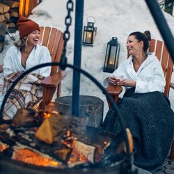 Nordik Spa-Nature Chelsea - A couple of friends visiting during the winter, sitting around a cozy fire for some laughs.