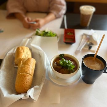 Coffee Factory - a woman sitting at a table with a sandwich and soup - Coffee & Tea Near Me - Westminster, California