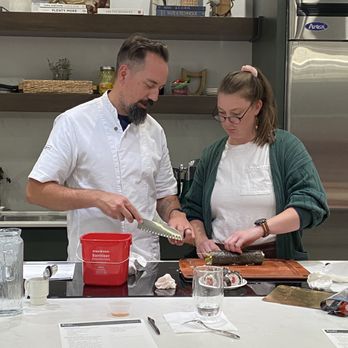 The Recipe - A man and woman are working together in a kitchen, preparing sushi on a cutting board with various kitchen items around them. - Venues & Event Spaces Near Me - Ames, Iowa