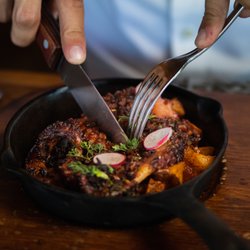 Latitud 32 - PULPO AL GRILL 
Cocinado y servido en una sartén de hierro fundido,
con aliño, aceite de trufa y paprika.