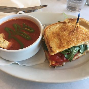 DeVivo's Eatery - The Stella sandwich (half portion) with tomato basil soup lunch menu. Look at the detailed design on the soup! Amazing. - New American Near Me - Keller, Texas