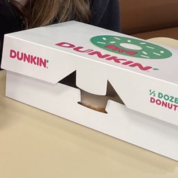 a woman sitting at a table with a box of donuts a woman sitting at a table with a box of donuts