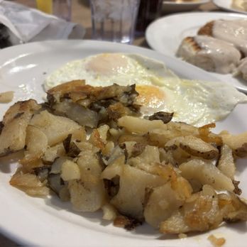 Starlight Diner - Hashbrowns and Eggs (2) - A breakfast plate featuring fried potatoes and sunny-side-up eggs, with other breakfast items visible on plates in the background. - Diners Near Me - Hanover, Pennsylvania