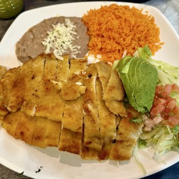 Taco Dále - Milanesa Dinner - A plate featuring fried fish fillets, Mexican rice, refried beans topped with cheese, and a side salad with lettuce, tomato, and dressing. - Mexican Near Me - Lisle, Illinois