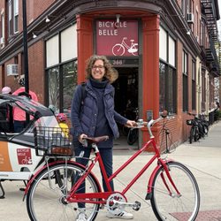 Bicycle Belle - Very happy middle aged white woman a red Brooklyn Bike Company Franklin style 3-speed bike in front of Bicycle Belle.