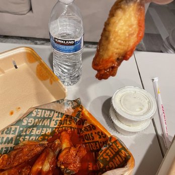 Wingstop - a hand dipping a piece of chicken wings - Chicken Wings Near Me - Brentwood, California Wingstop - a hand dipping a piece of chicken wings - Chicken Wings Near Me - Brentwood, California