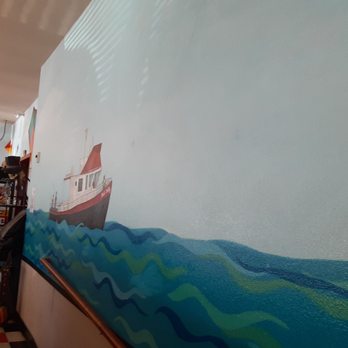 Hungry Harbor Grille - a man painting a mural on a wall - Burgers Near Me - Long Beach, Washington