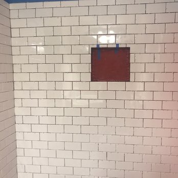 Honey Do - a white tiled bathroom with a red window - Landscaping Near Me