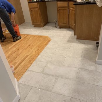 Kola Construction - a man working on a kitchen floor - General Contractors Near Me