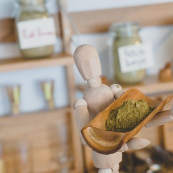 Qi Kratom CBD Tea - a hand holding a wooden spoon with a green tea powder in it - Vitamins & Supplements Near Me - Evanston, Illinois Qi Kratom CBD Tea - a hand holding a wooden spoon with a green tea powder in it - Vitamins & Supplements Near Me - Evanston, Illinois