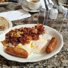 Two eggs over medium with potatoes and sausage and rye toast