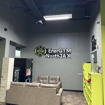 EnerGYM NorthJAX - Waiting/lounge area at EnerGYM NorthJAX with couches, vending machines, lockers, and the gym logo on the wall. - Gyms Near Me - Jacksonville, Florida EnerGYM NorthJAX - Waiting/lounge area at EnerGYM NorthJAX with couches, vending machines, lockers, and the gym logo on the wall. - Gyms Near Me - Jacksonville, Florida