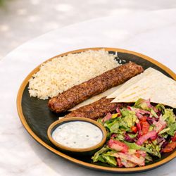 Adana kebab, grilled ground lamb served with rice, salad, and pita.