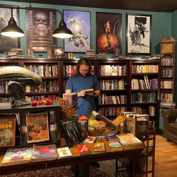 Other Skies Weird Fiction - The main room of the bookstore, complete with sci-fi and fantasy artwork above a wall of bookshelves.