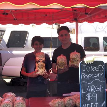 Jorges Kettle Corn - two people standing under a tent - Food Stands Near Me Jorges Kettle Corn - two people standing under a tent - Food Stands Near Me
