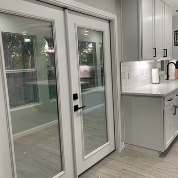 O&E Remodeling - a kitchen with white cabinets and glass doors - General Contractors Near Me