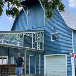 a man standing in front of a blue barn a man standing in front of a blue barn