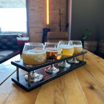 Headflyer Brewing - The flight - Four glasses of beer are arranged on a black flight paddle on a wooden table in a brewery or bar setting. - Breweries Near Me - Minneapolis, Minnesota