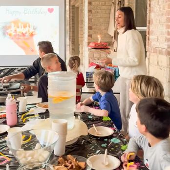 The Playwell Club - Kids gathered around a long table during an indoor birthday moment, watching a cake with candles while crafting, snacking, and celebrating t - Venues & Event Spaces Near Me - Round Rock, Texas The Playwell Club - Kids gathered around a long table during an indoor birthday moment, watching a cake with candles while crafting, snacking, and celebrating t - Venues & Event Spaces Near Me - Round Rock, Texas