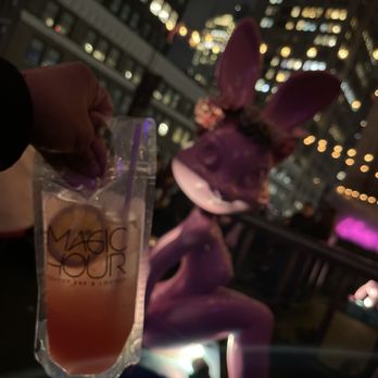 Bar Moxy - a person holding up a drink - Lounges Near Me - New York, New York Bar Moxy - a person holding up a drink - Lounges Near Me - New York, New York