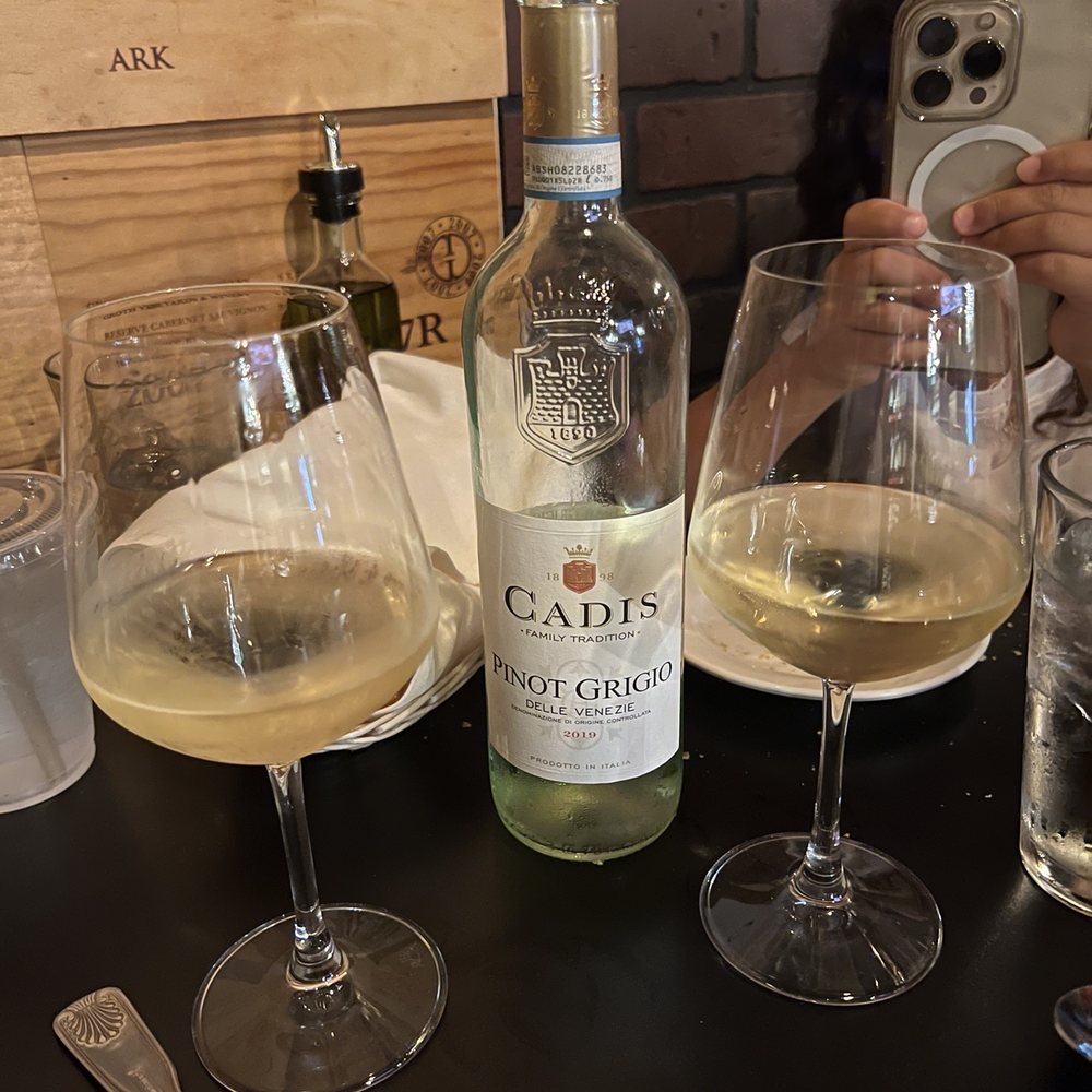 Anacapri - a woman taking a picture of wine glasses and a bottle - Italian Near Me - Pinecrest, Florida