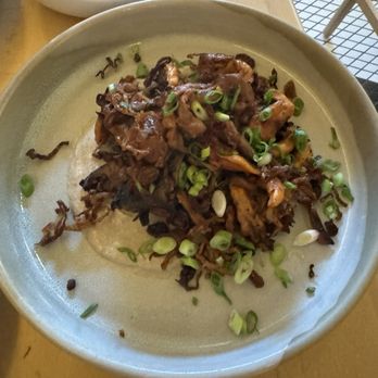 Baleia - Grilled Mushroom - A ceramic plate holds cooked shredded meat topped with chopped green onions, set on a wooden table. - Wine Bars Near Me - Boston, Massachusetts