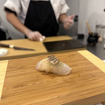 Fuku Omakase - a chef in the background - Sushi Bars Near Me - New York, New York Fuku Omakase - a chef in the background - Sushi Bars Near Me - New York, New York