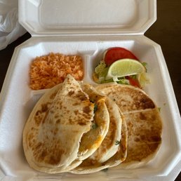 Gorditas - A foam takeout box contains two tacos, Mexican rice, and a small salad with tomato and lime wedge, typical of Mexican cuisine.