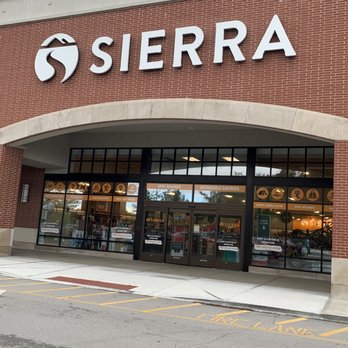 Sierra - Sierra sporting goods store front with large sign, glass doors, and windows displaying promotional banners. - Outdoor Gear Near Me - Carmel, Indiana