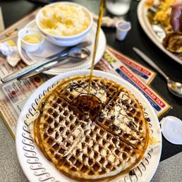 a plate of waffles with syrup being poured on top