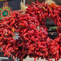 Farmers Chile Market - red chile ristra wreaths in front of Farmers Chile Market sign