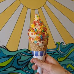 a hand holding an ice cream cone with sprinkles