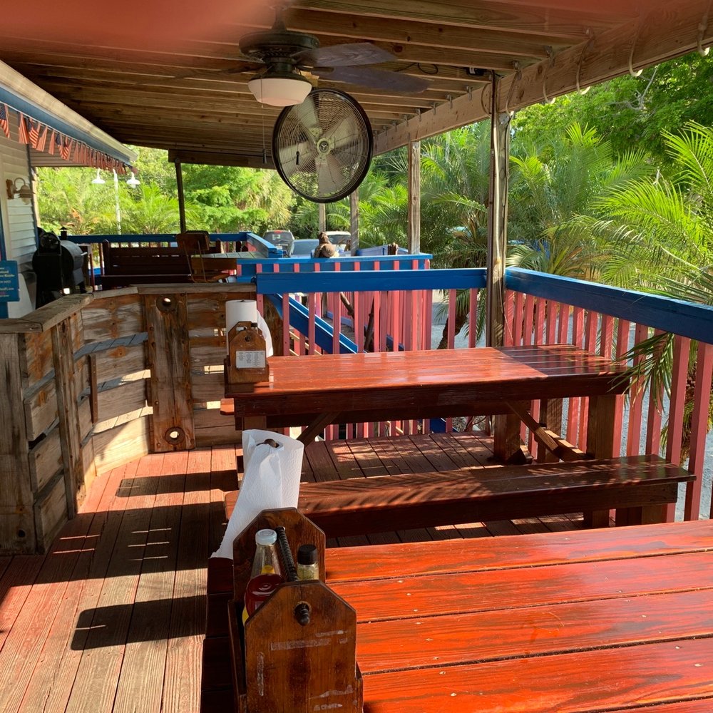 Lazy Flamingo - a wooden deck with tables and a clock - Seafood Near Me - Bokeelia, Florida Lazy Flamingo - a wooden deck with tables and a clock - Seafood Near Me - Bokeelia, Florida