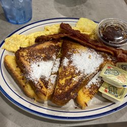 French toast with powdered sugar. Scrambled eggs and bacon.