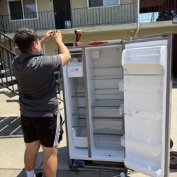 A people working to take off the refrigerator door