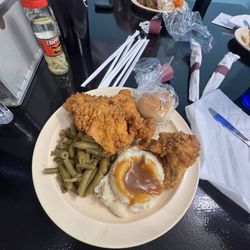 Fried chicken with mashed potatoes and gravy, with some green beans.