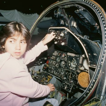 Tillamook Air Museum - Child sitting in cockpit of airplane in museum, touching the controls. - Museums Near Me - Tillamook, Oregon Tillamook Air Museum - Child sitting in cockpit of airplane in museum, touching the controls. - Museums Near Me - Tillamook, Oregon
