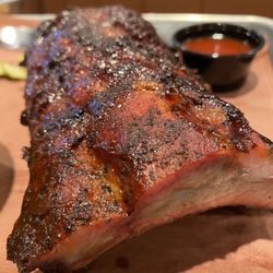 Jim 'N Nick's Bar-B-Q - Jim 'N Nick's hickory-smoked baby back ribs, glistening with caramelized bark and served with a side of house BBQ sauce.