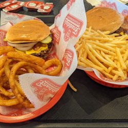 Freddy's Frozen Custard & Steakburgers - Bacon and cheese double steak burger (right) with fries, Bacon and cheese double steak burger ((left) with onion rings.