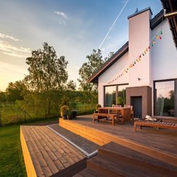 Denver Patio Masters - Wood deck with outdoor dining at sunset by Denver Patio Masters in Centennial, Colorado.