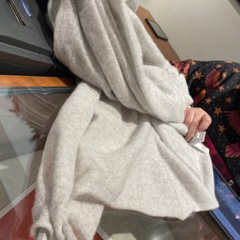 J.Crew - A light gray, knit sweater with a zipper is placed on a glass table, with a Christmas tree and a person in festive pajamas in the background. - Men's Clothing Near Me - Austin, Texas