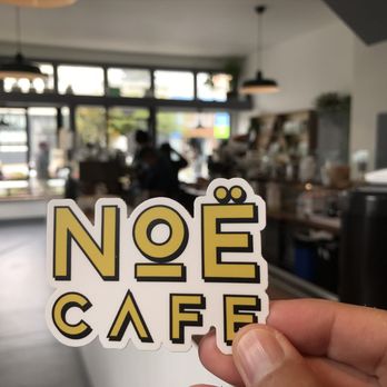 Noe Cafe - a person holding up a sticker - Coffee Roasteries Near Me - San Francisco, California Noe Cafe - a person holding up a sticker - Coffee Roasteries Near Me - San Francisco, California