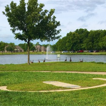 Centennial Park - A human sundial in the foreground tells time with an adult's shadow. Lake fountain in the background. - Parks Near Me - Owasso, Oklahoma