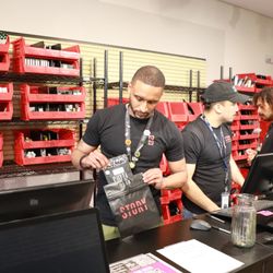 Story Cannabis - Employee wearing a black story logo shirt in front of red product bins on black shelves loading a customers order into a story exit bag