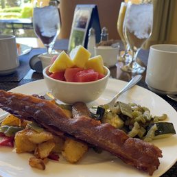 a plate of bacon, potatoes, and fruit a plate of bacon, potatoes, and fruit