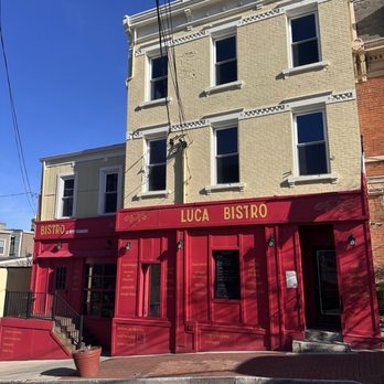 Luca Bistro - Exterior - Luca Bistro's storefront features a red exterior with signage, set against a three-story yellow brick building with multiple windows. - French Near Me - Cincinnati, Ohio